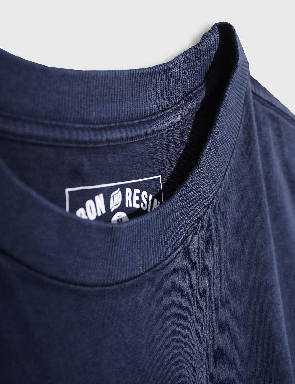 Close-up of a navy T-shirt collar with visible "Iron and Resin" label inside, showcasing fabric texture and stitching detail.