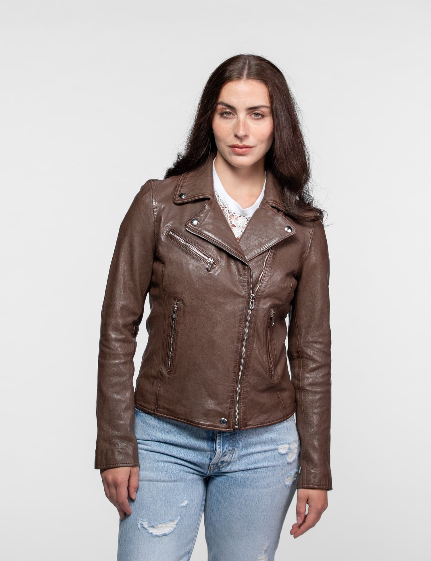 Femme en blouson marron, haut blanc et jean bleu.