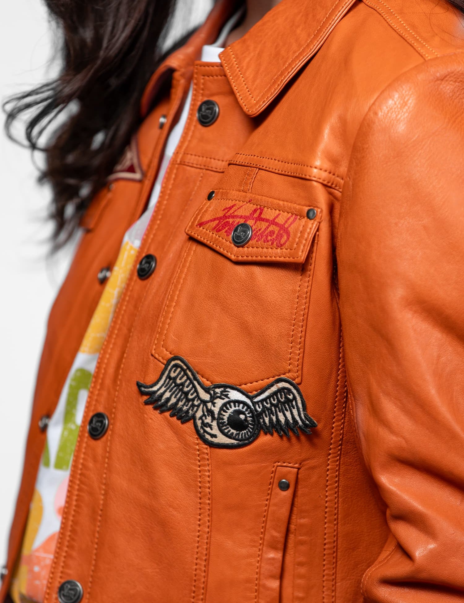 Veste en cuir orange avec patchs Von Dutch et boutons.