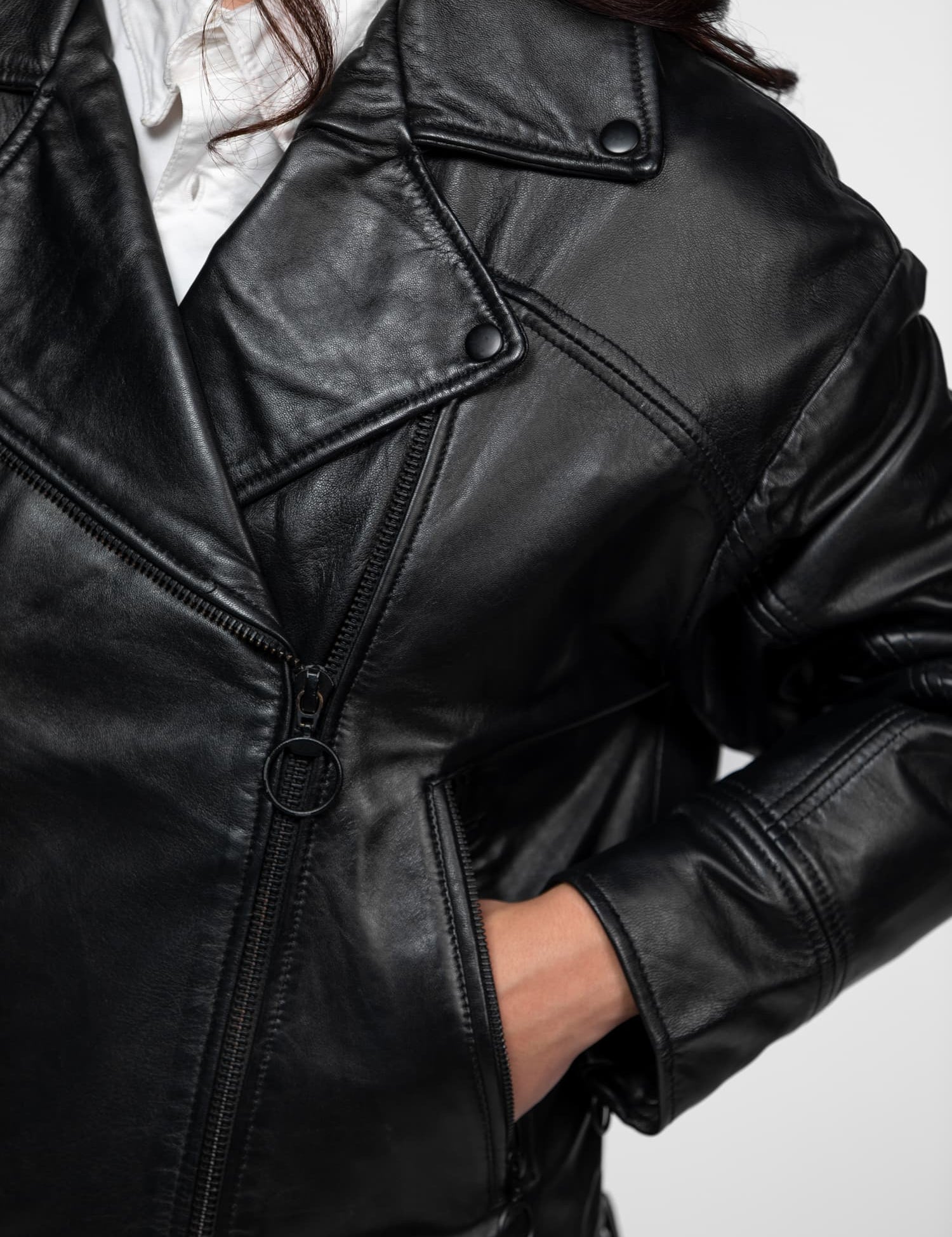 Veste de motard noire en cuir avec fermetures éclair métalliques.