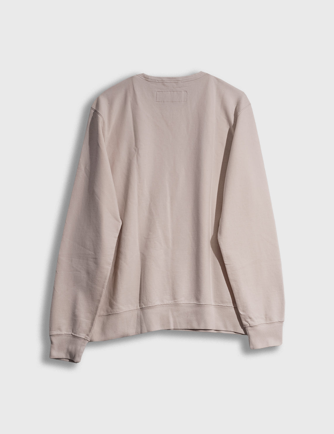 Back view of a plain beige sweatshirt on a white background, showcasing its simple design and soft fabric texture.