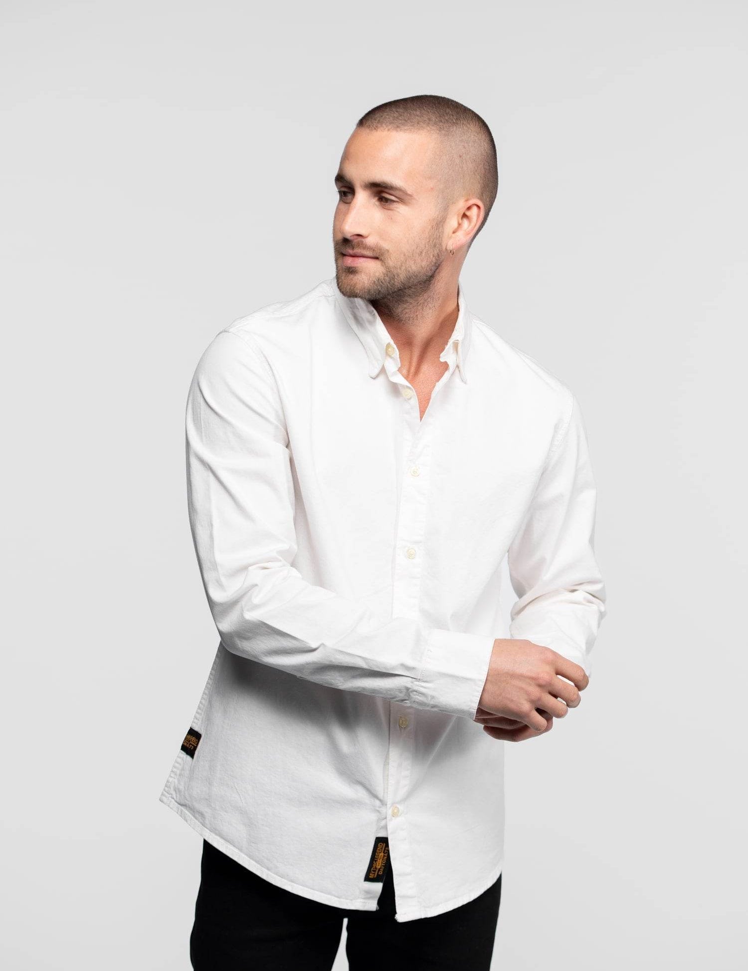 Homme portant une chemise blanche et un pantalon noir.