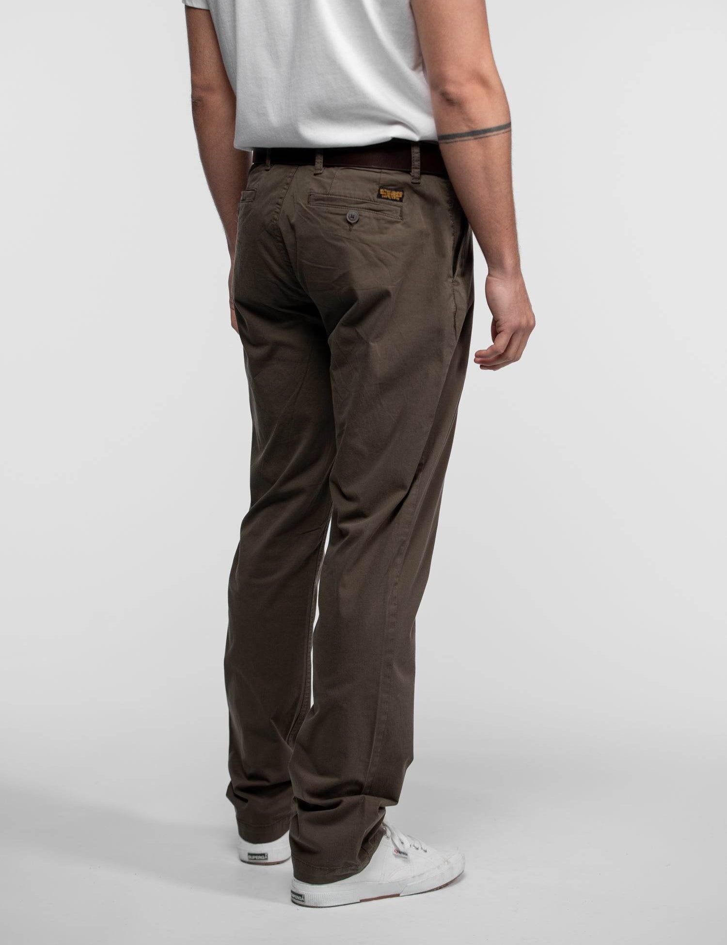 Homme de dos portant un pantalon marron et baskets.
