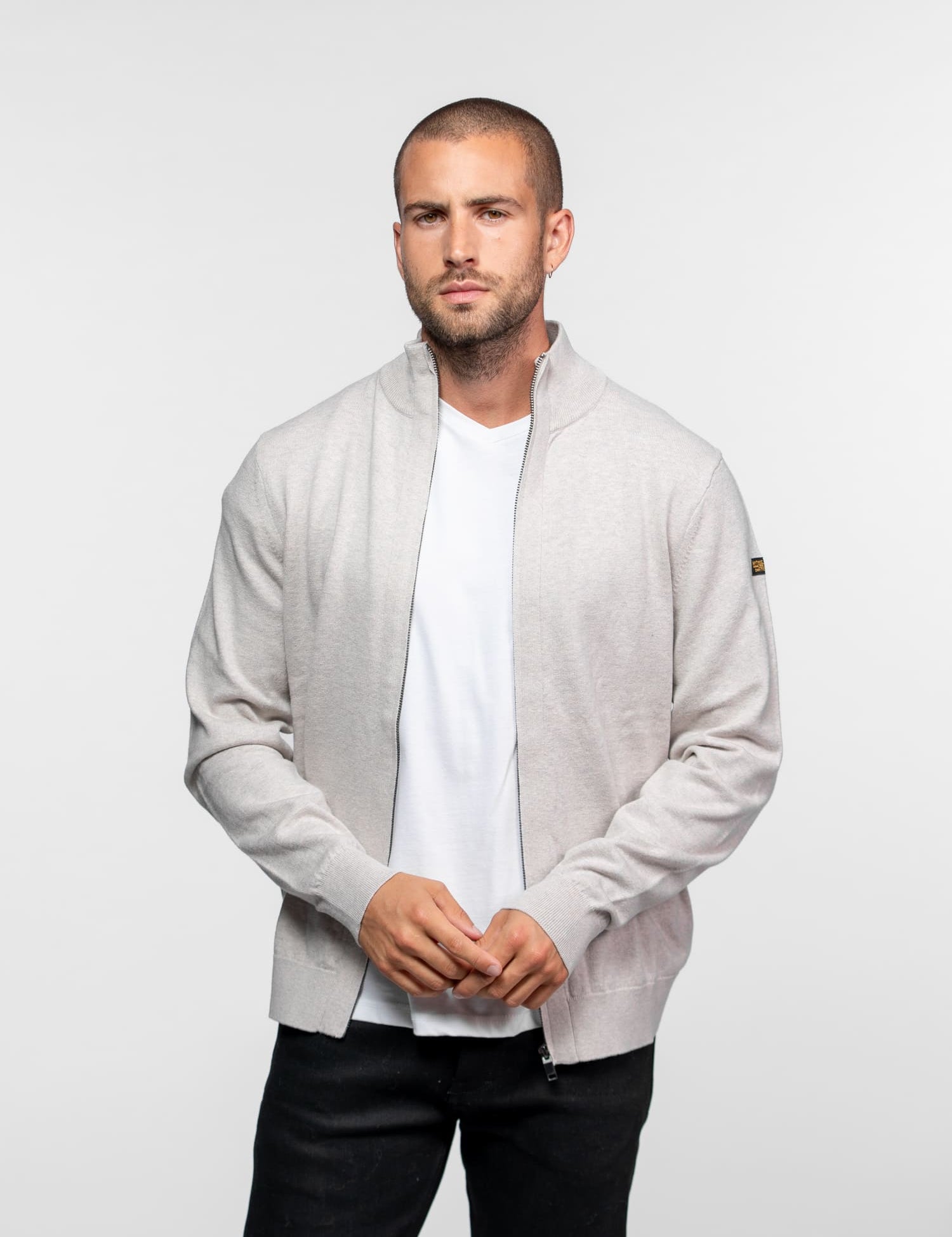 Gilet zippé beige clair avec écusson logo sur la manche.