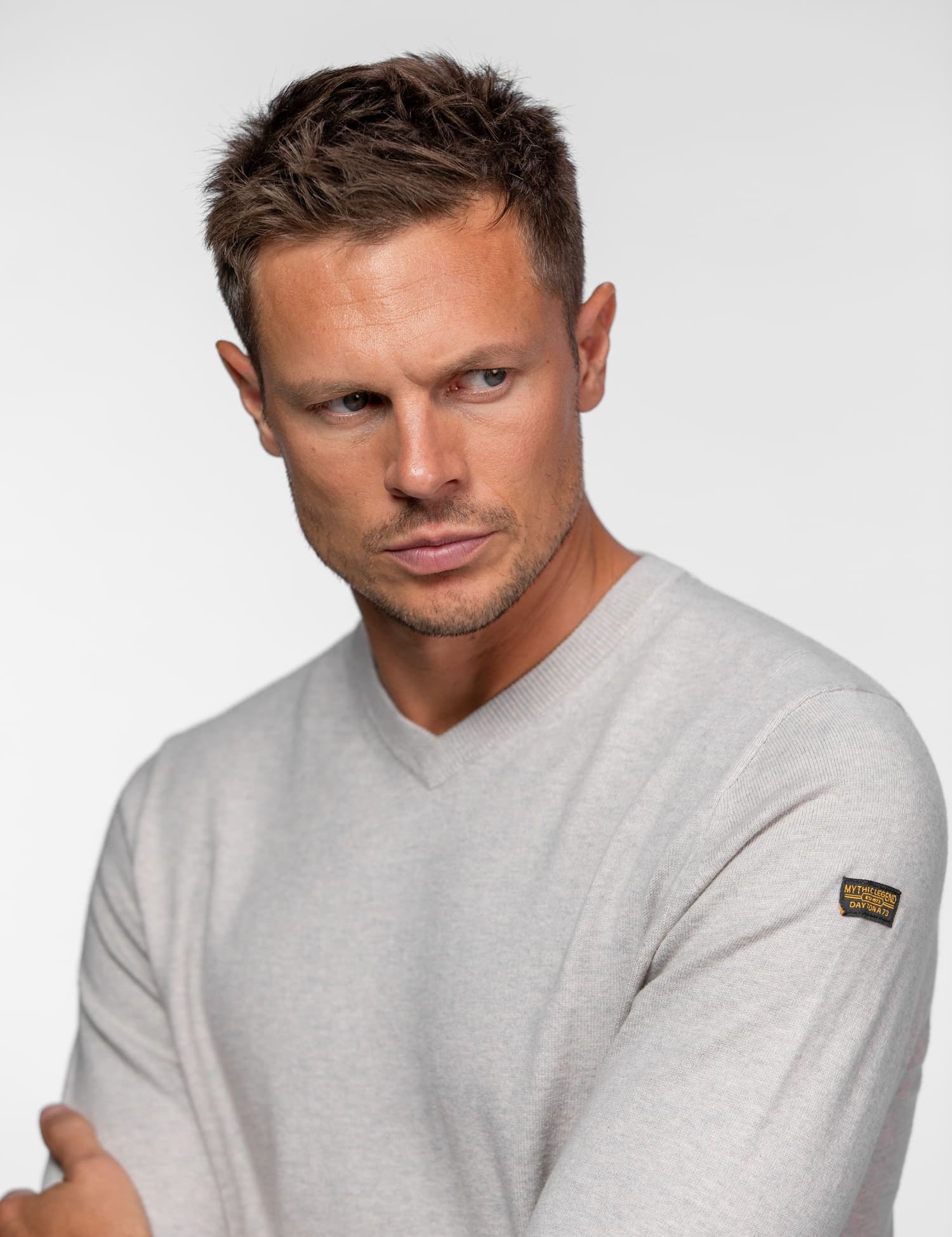 Gros plan sur un homme portant un pull beige.
