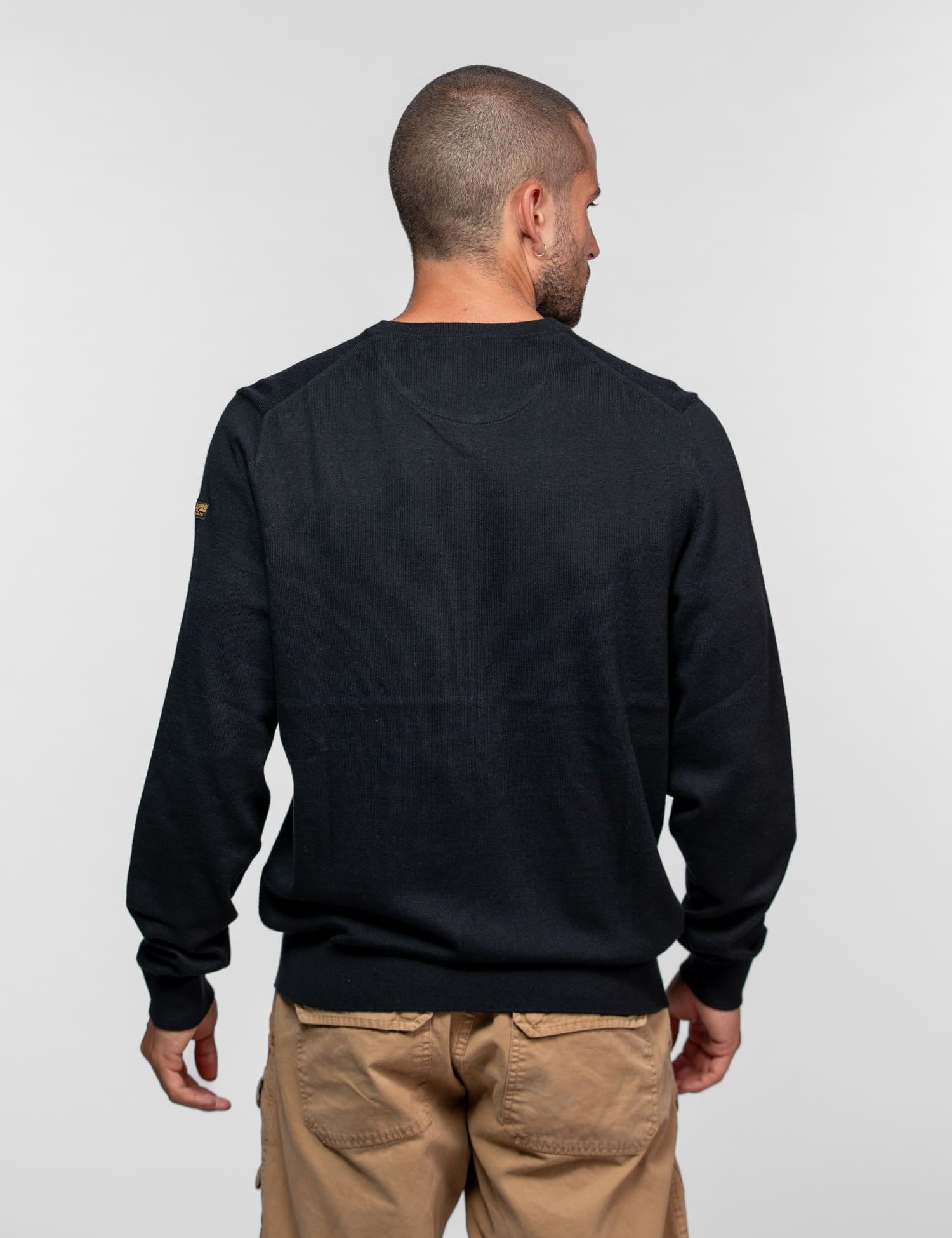 Pull noir à manches longues avec écusson sur l'épaule.