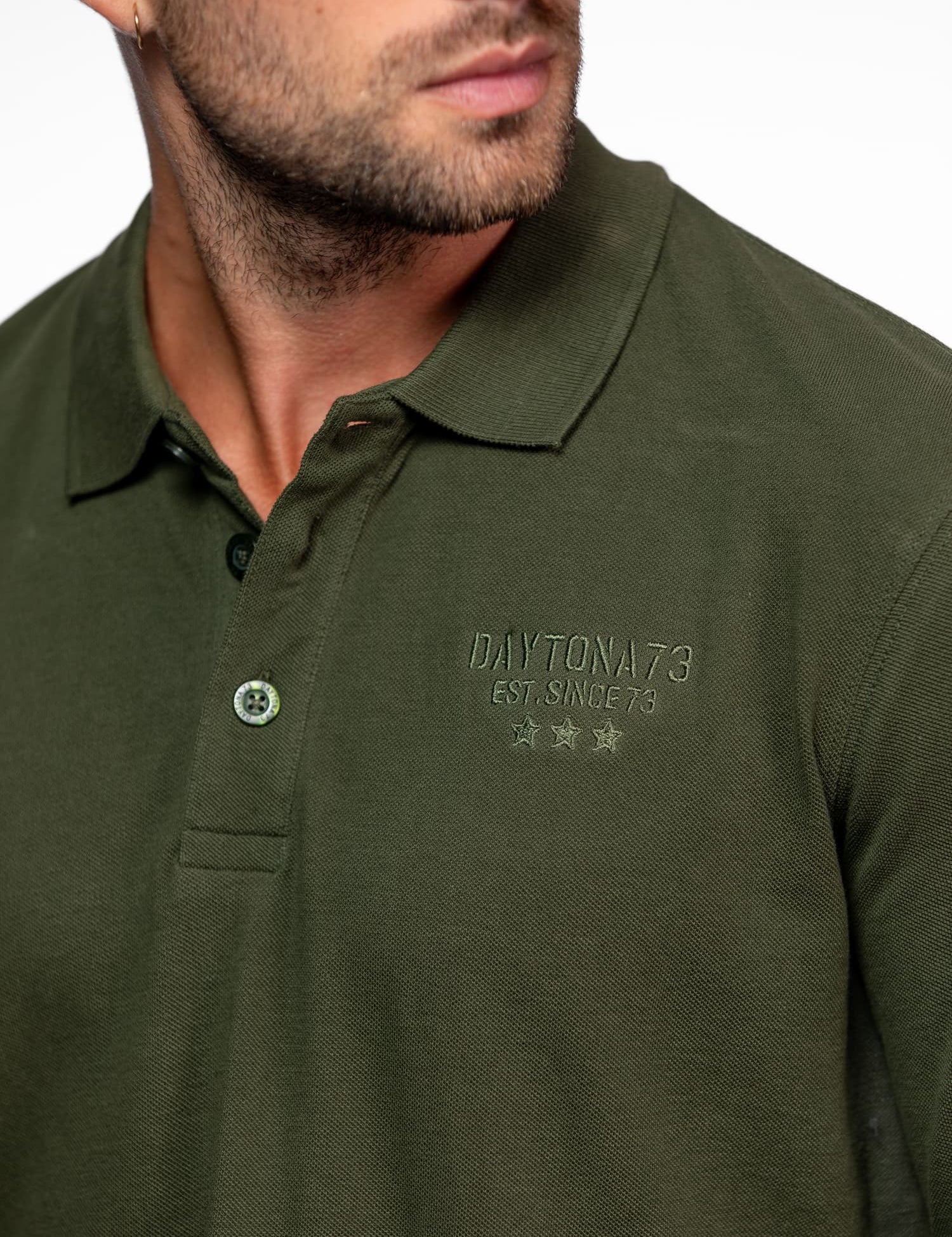 Gros plan sur un polo kaki avec logo brodé.