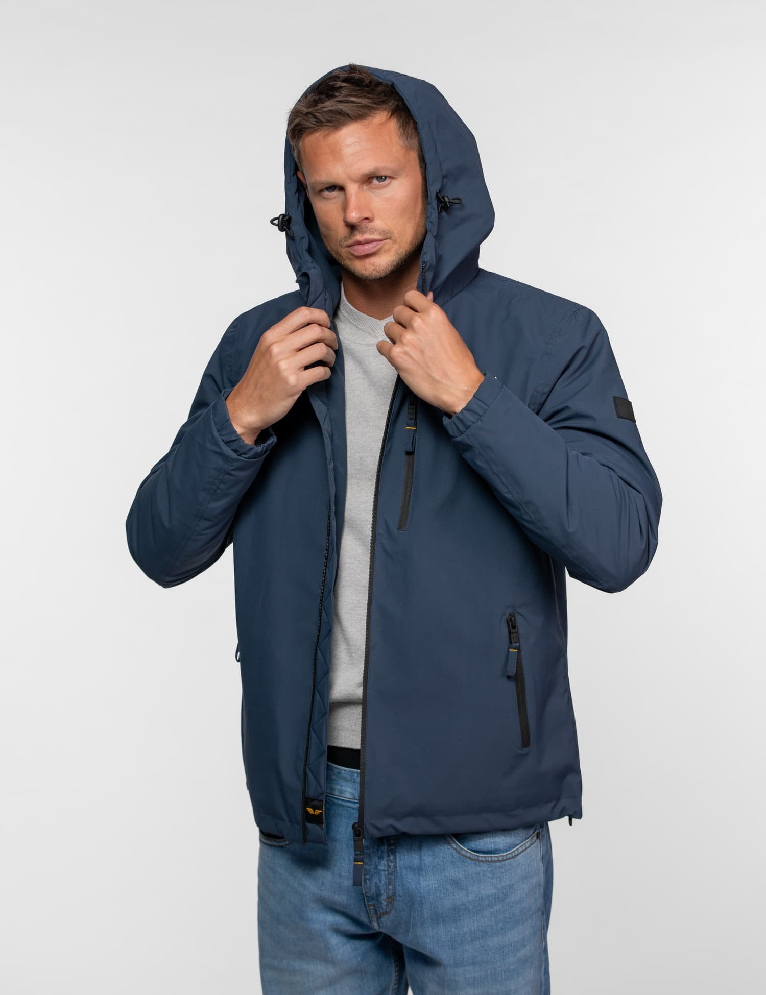 Veste à capuche bleu marine avec fermetures éclair et écusson.