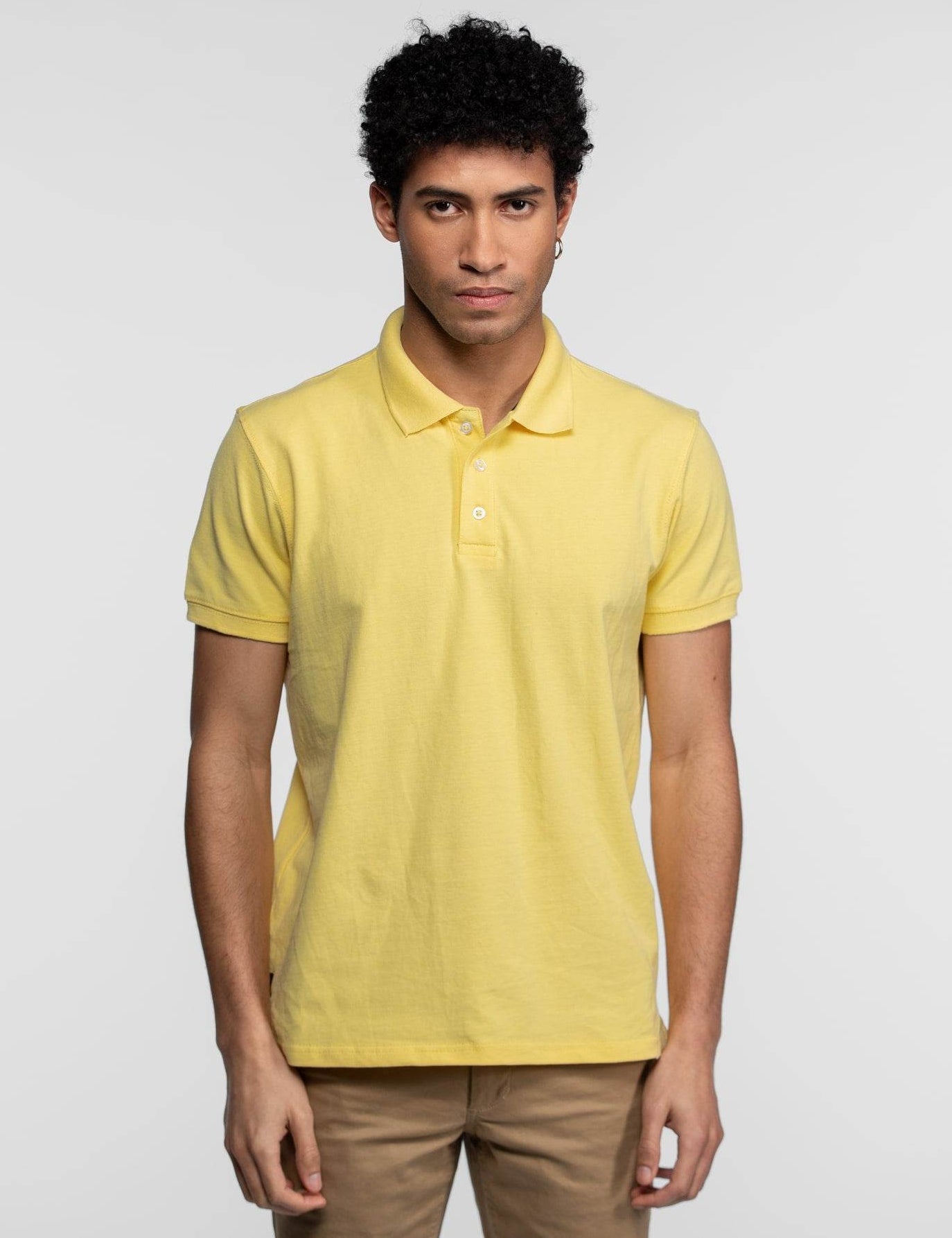 Polo jaune pastel à manches courtes avec trois boutons blancs.
