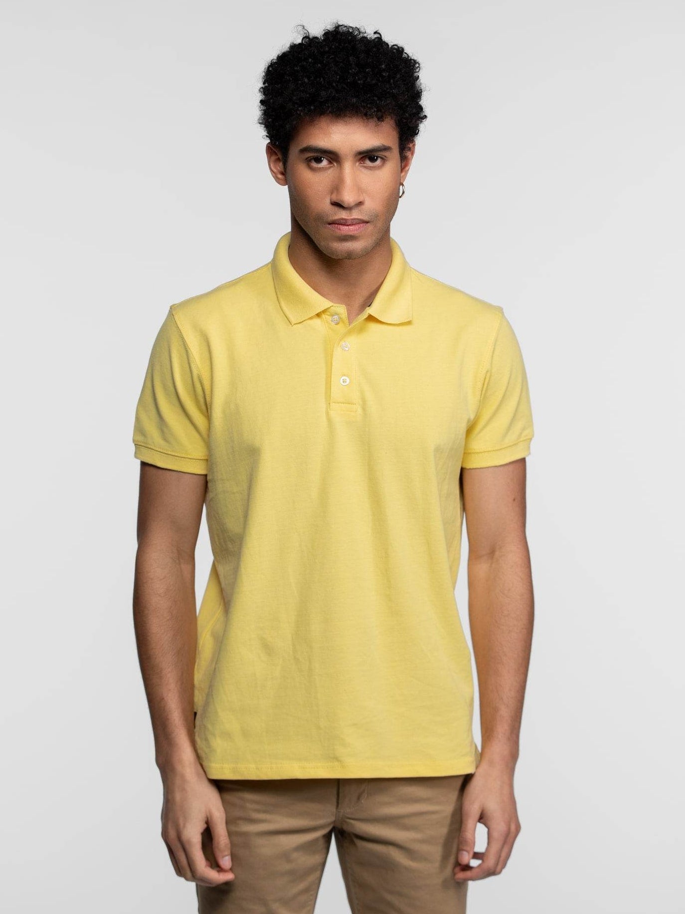 Polo jaune pastel à manches courtes avec trois boutons blancs.