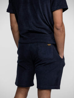 Homme vu de dos, portant un short et un t-shirt bleu marine.