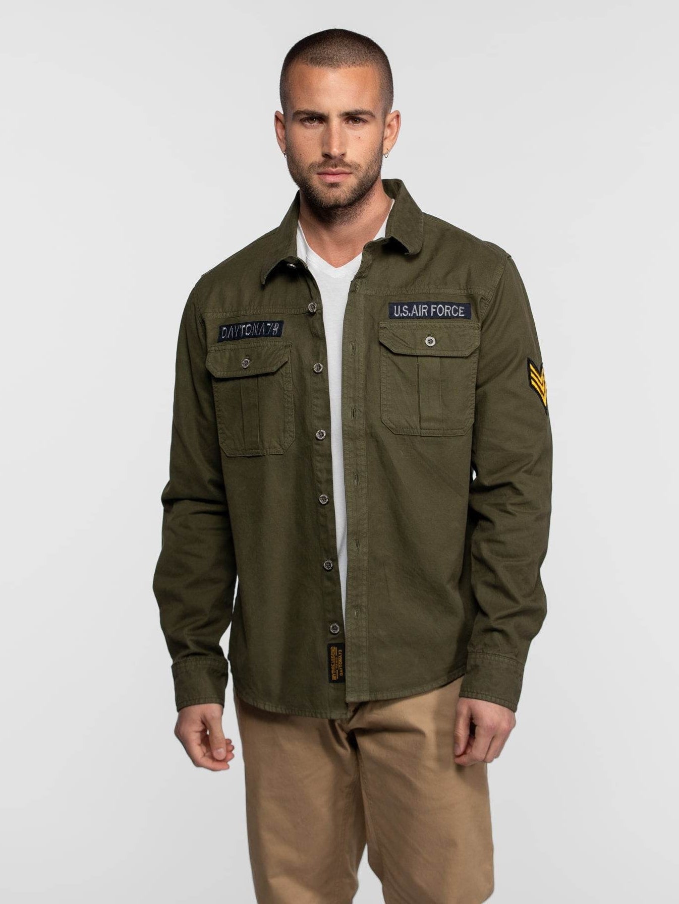 Homme en chemise militaire olive et pantalon kaki.