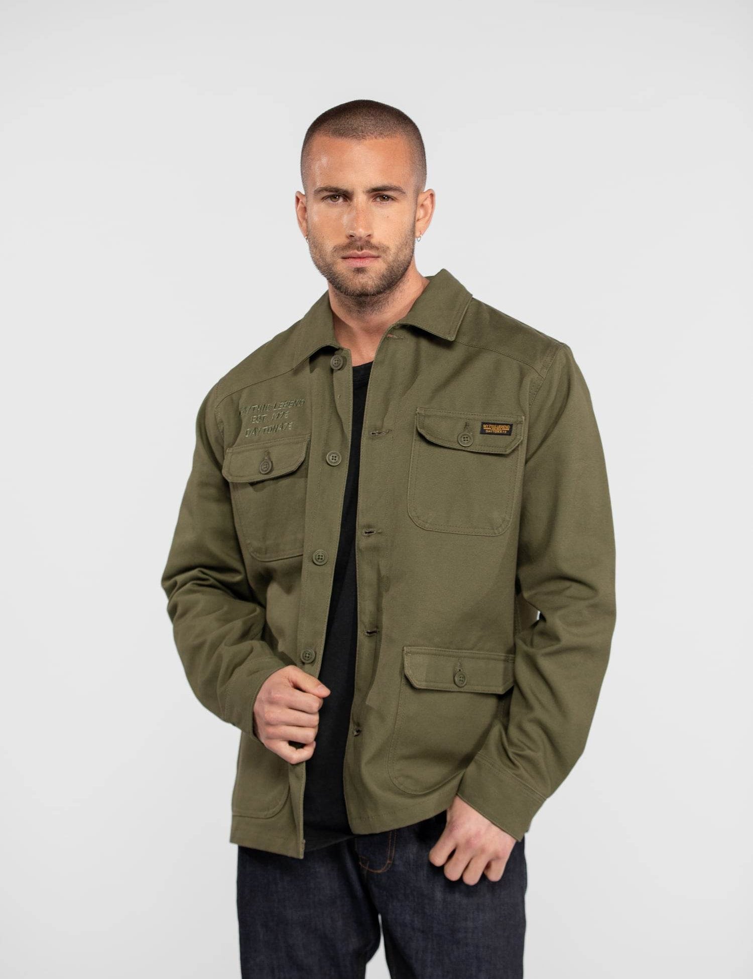 Homme portant une veste vert kaki et un jean.