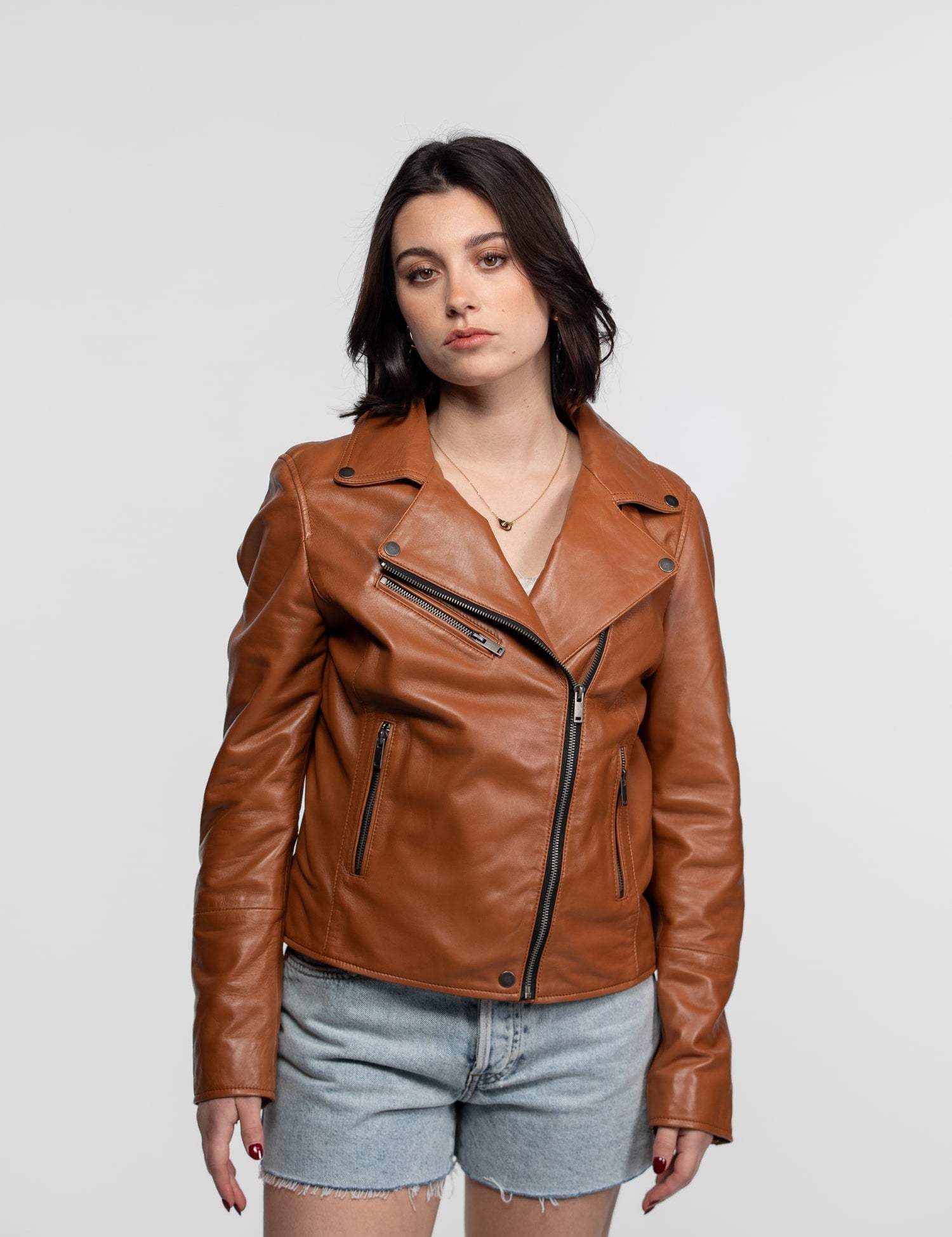 Femme portant une veste en cuir marron et short.