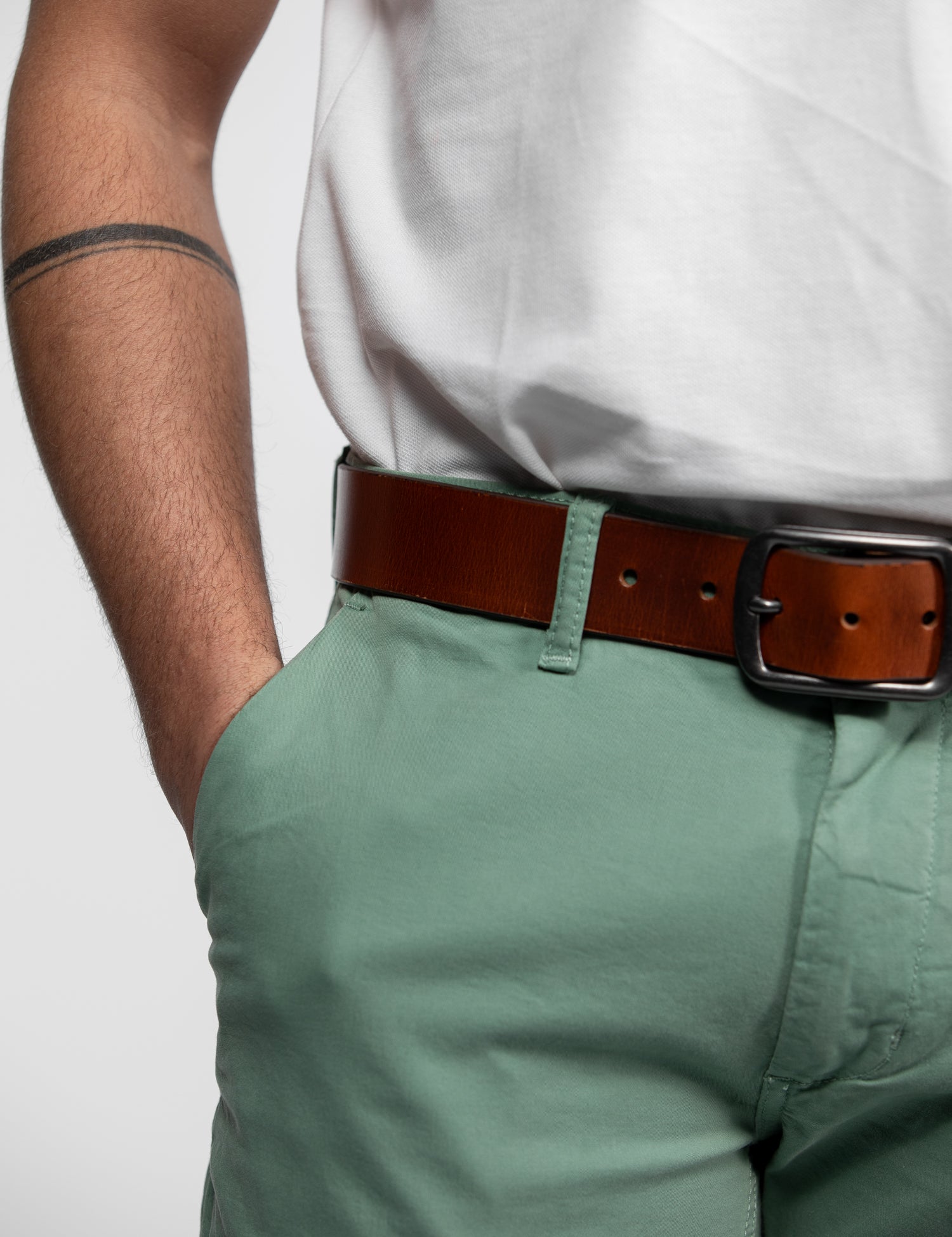 Pantalon vert, ceinture marron et t-shirt blanc.