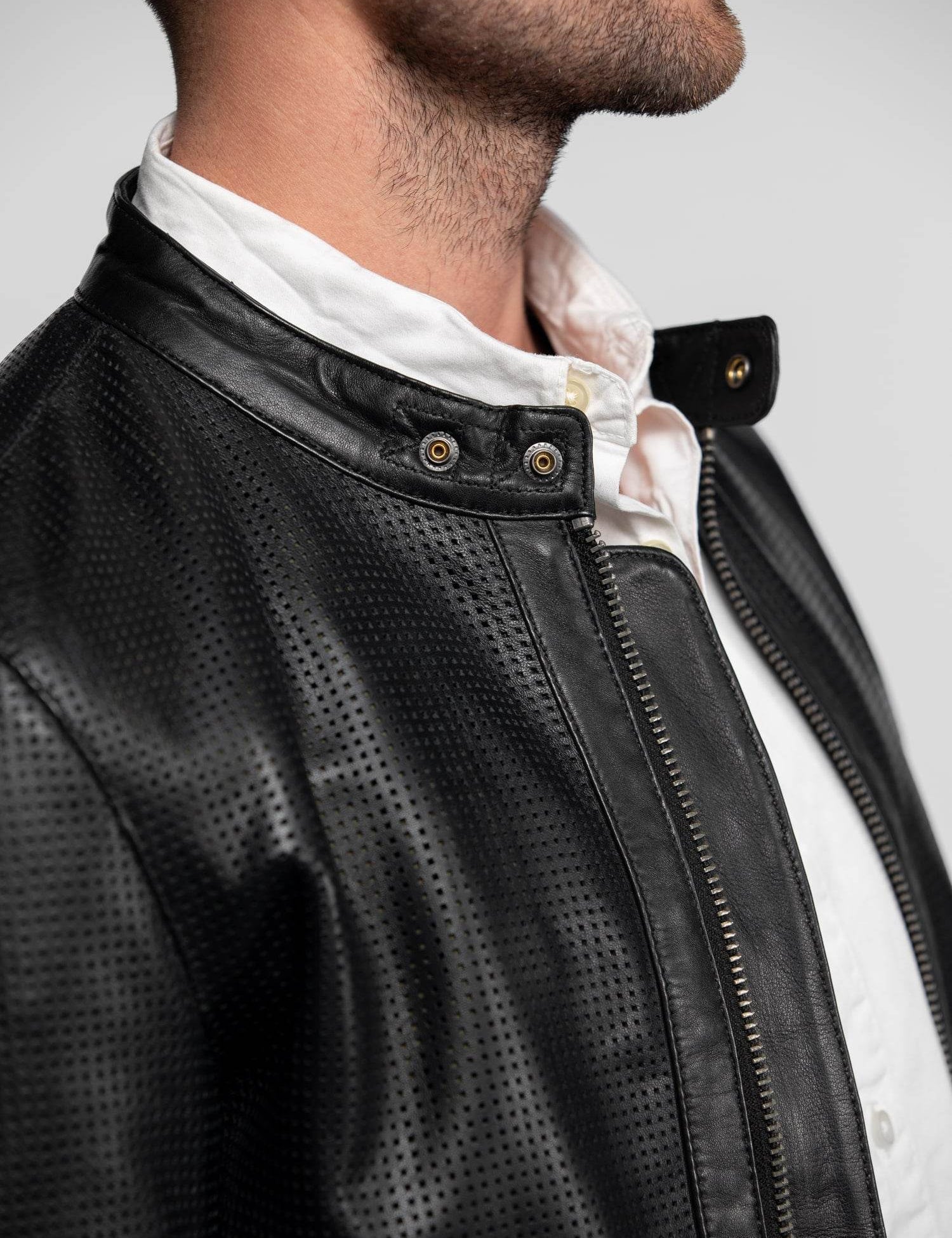 Blouson en cuir noir perforé avec col à boutons-pression.