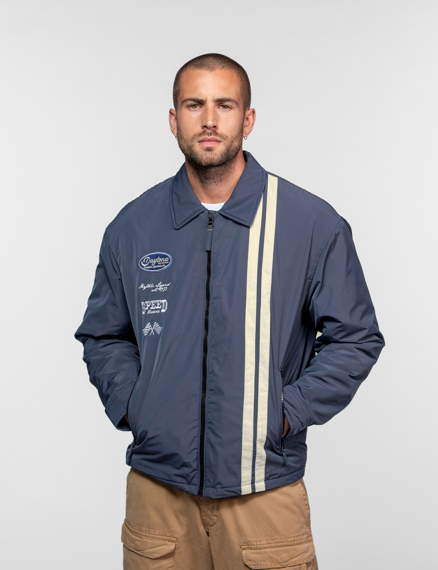 Homme portant un blouson bleu avec deux bandes verticales.