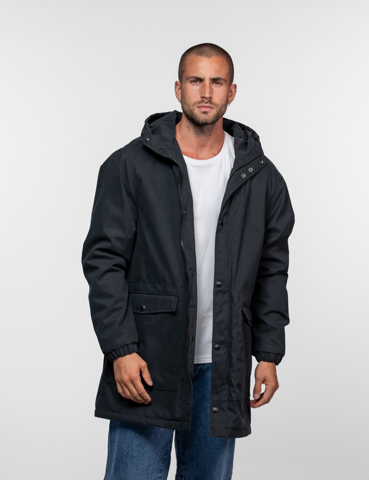 Homme portant une parka noire à capuche et t-shirt blanc.