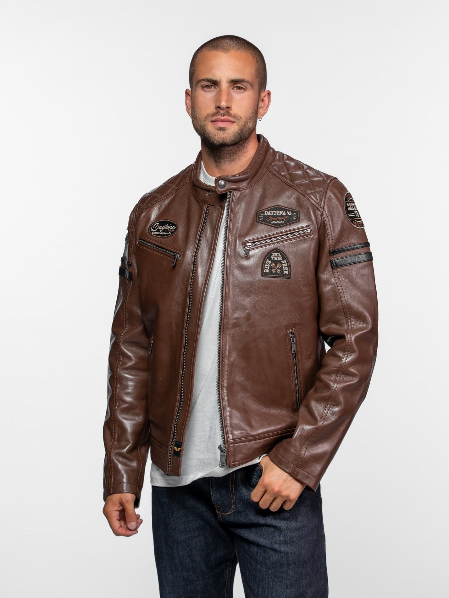 Veste en cuir marron avec écussons, fermetures éclair et matelassage.