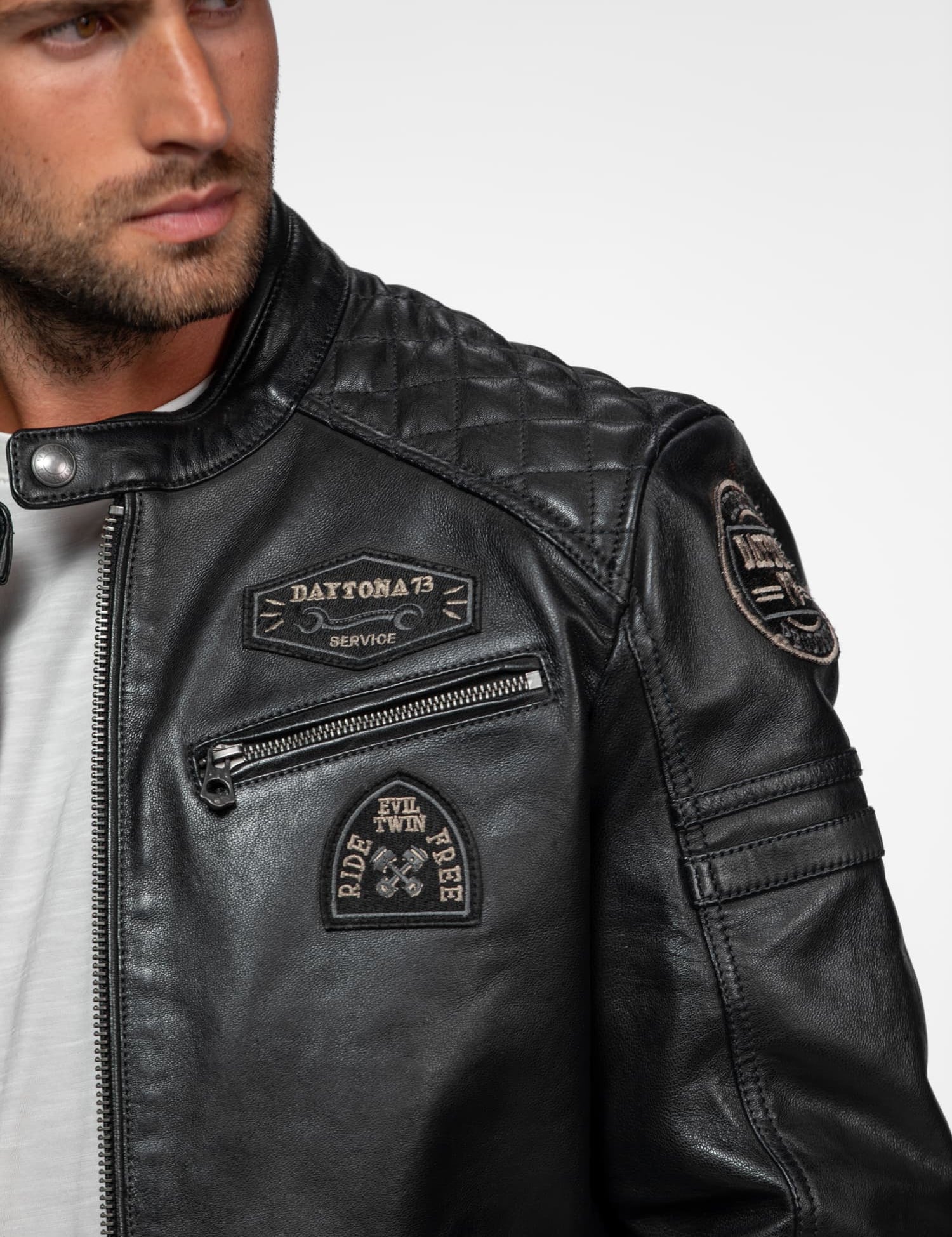 Blouson en cuir noir avec écussons Daytona 73 et fermetures.