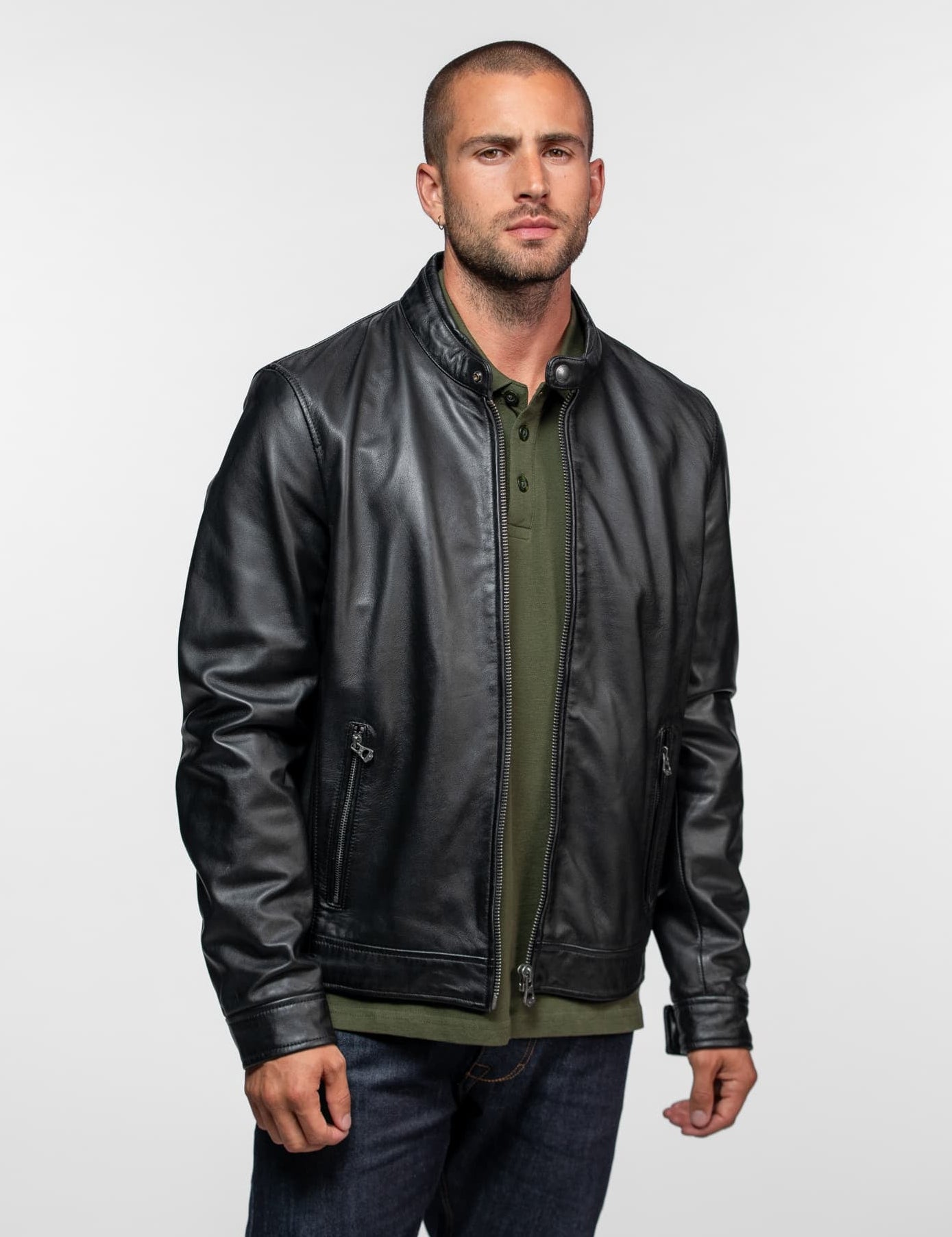 Homme en blouson noir, polo kaki et jean bleu.