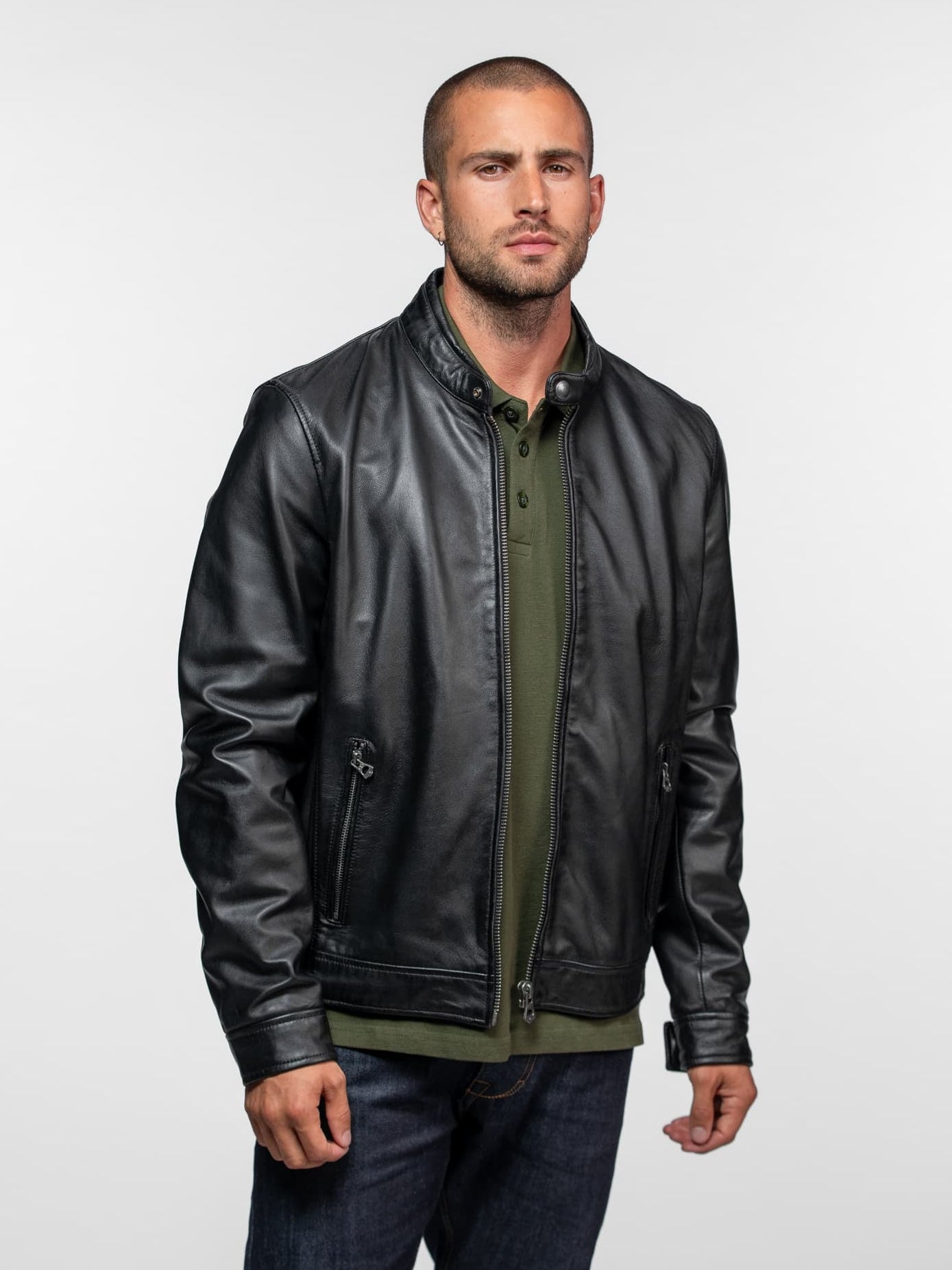 Homme en blouson noir, polo kaki et jean bleu.