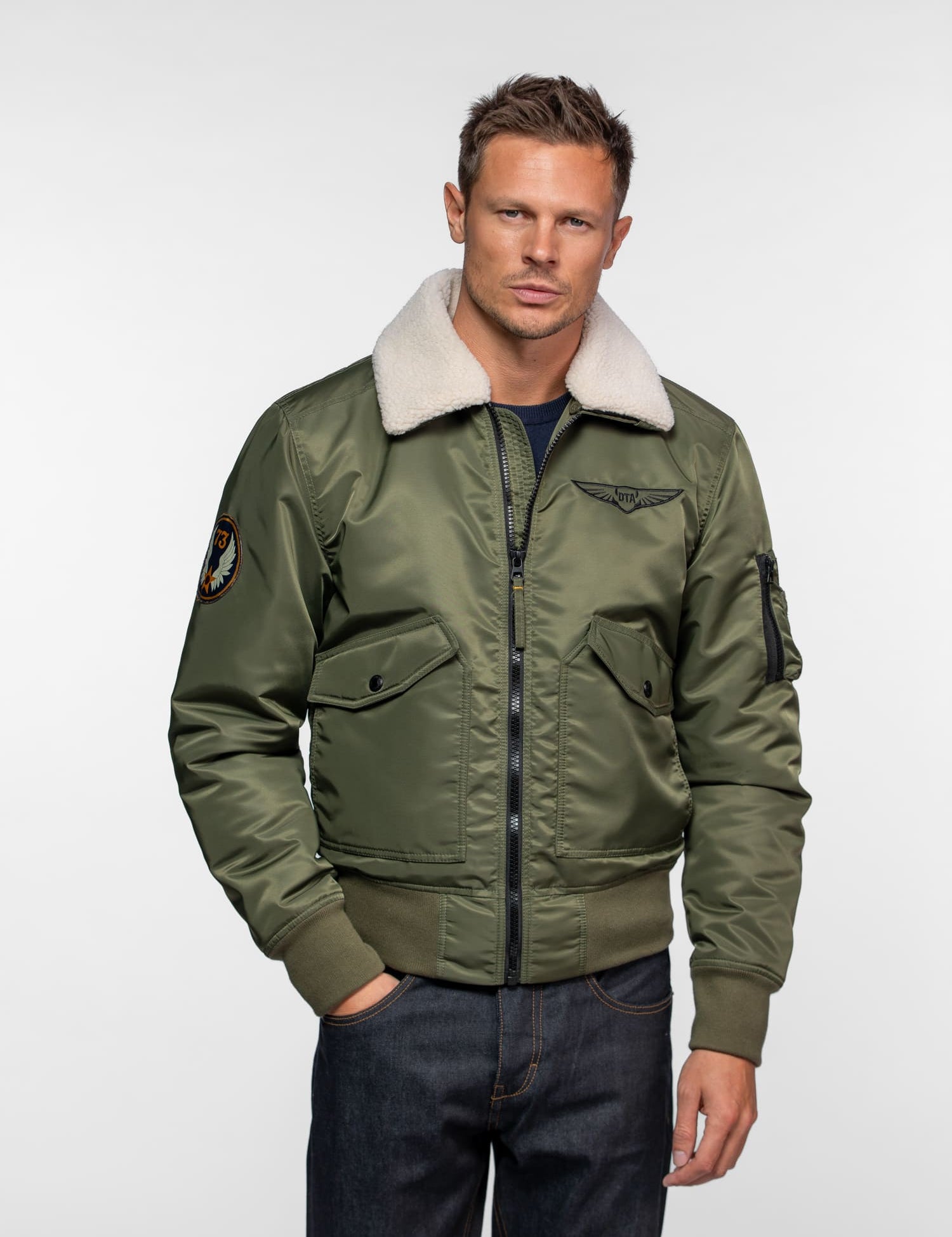 Homme portant un blouson vert olive avec col blanc.