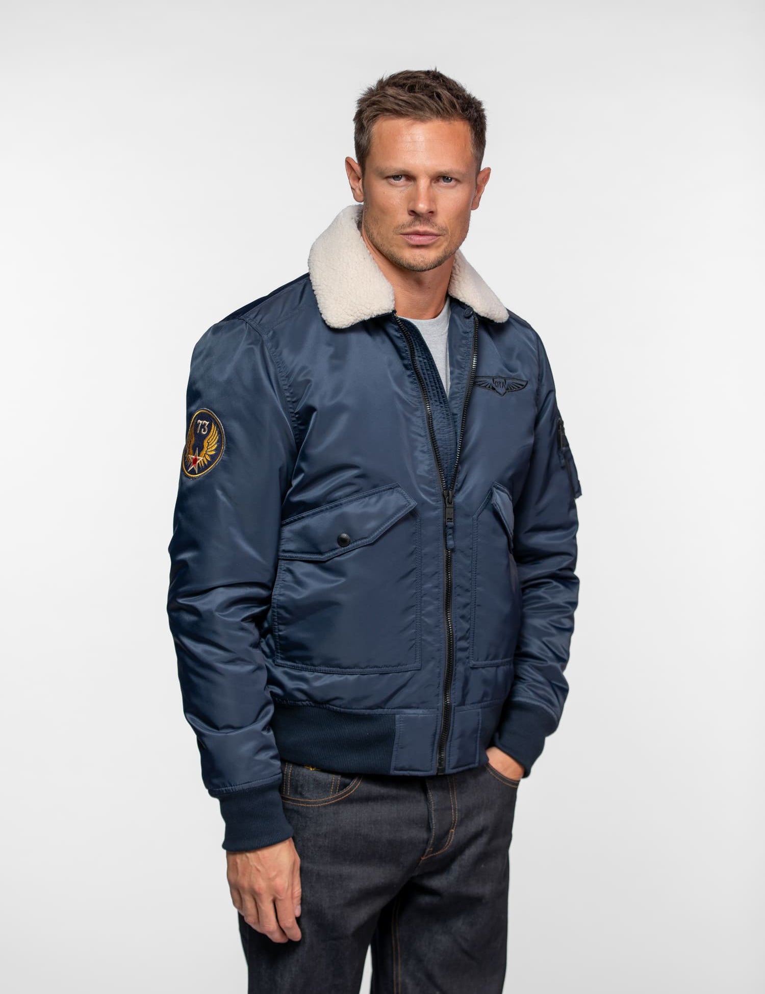 Blouson aviateur bleu avec col en laine blanche.
