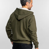 Homme aux cheveux gris, vêtu d'un sweat à capuche vert et d'un pantalon noir, vu de dos, sur fond blanc uni.