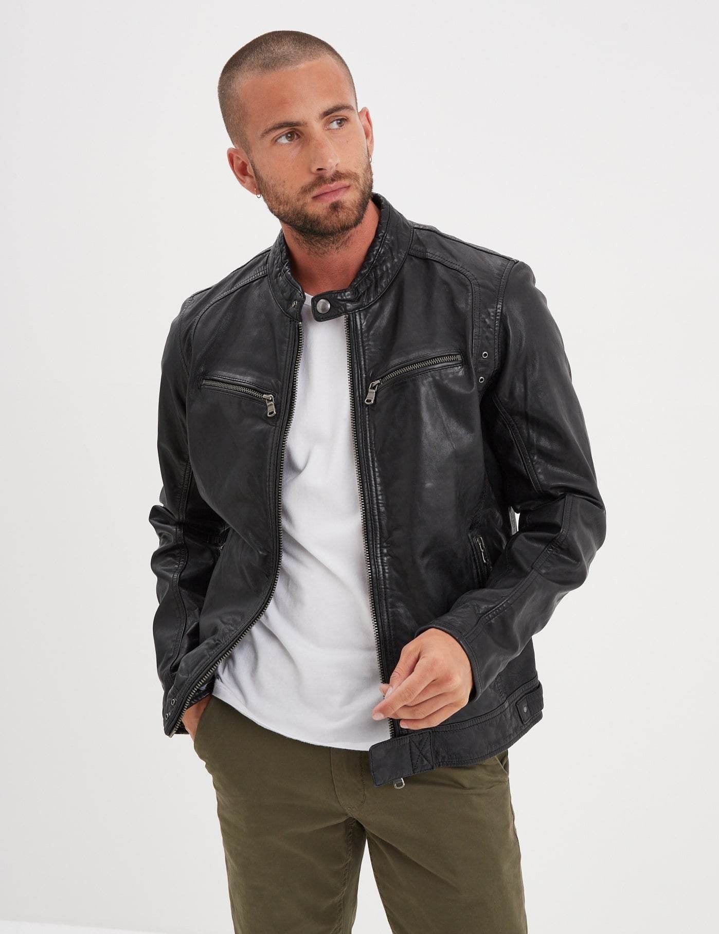 Veste en cuir noir sur t-shirt blanc et pantalon vert.