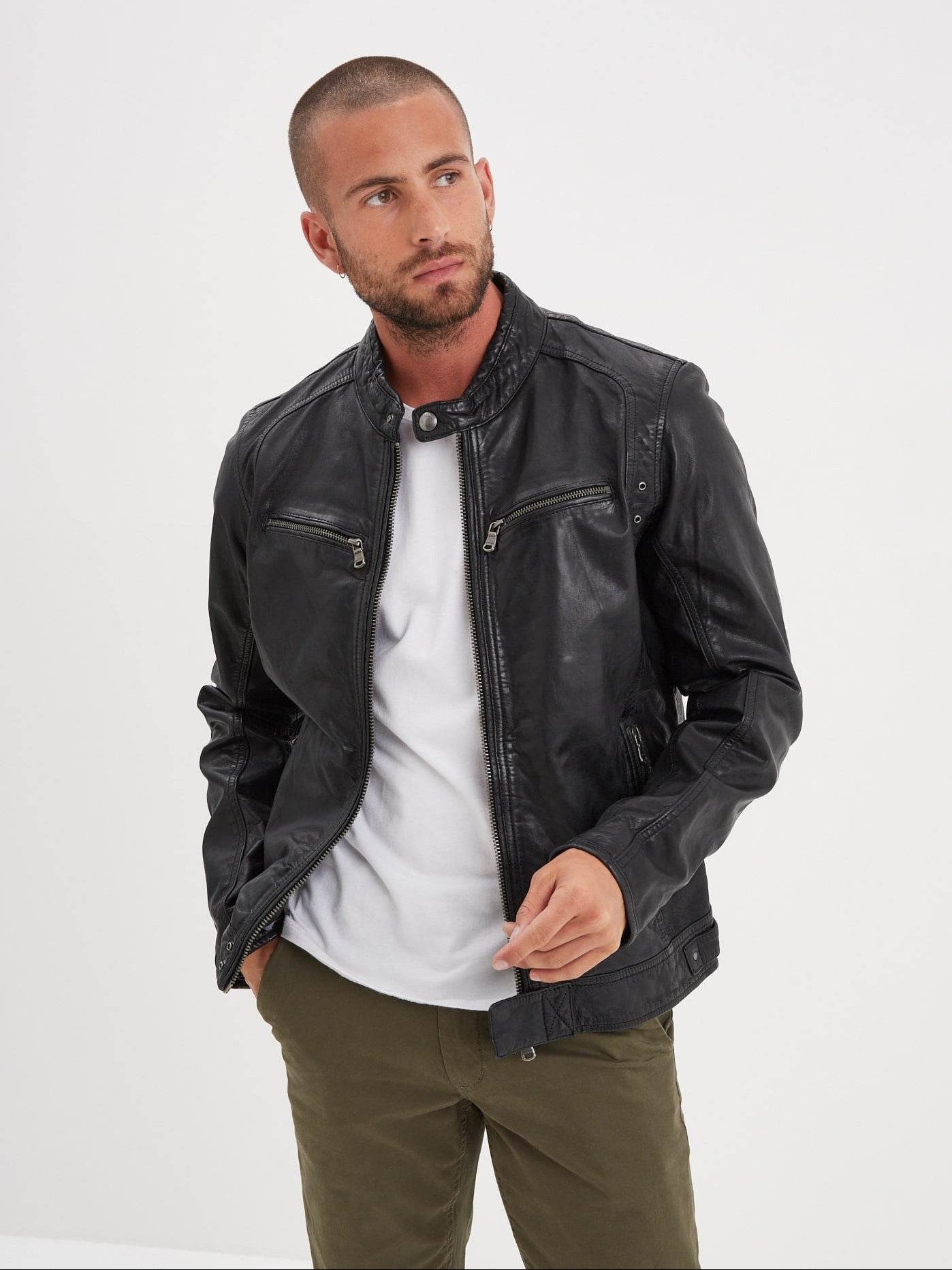 Veste en cuir noir sur t-shirt blanc et pantalon vert.