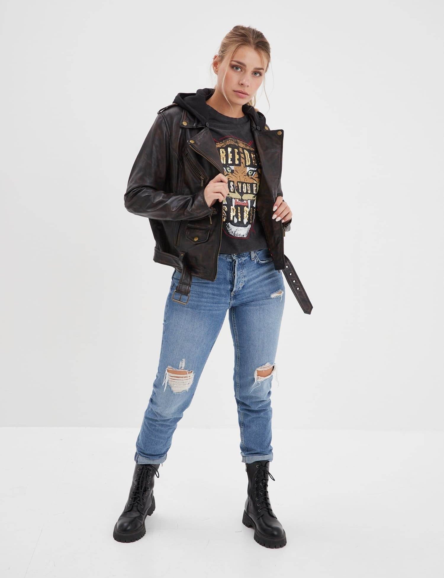 Femme portant un blouson en cuir, jean et bottes.