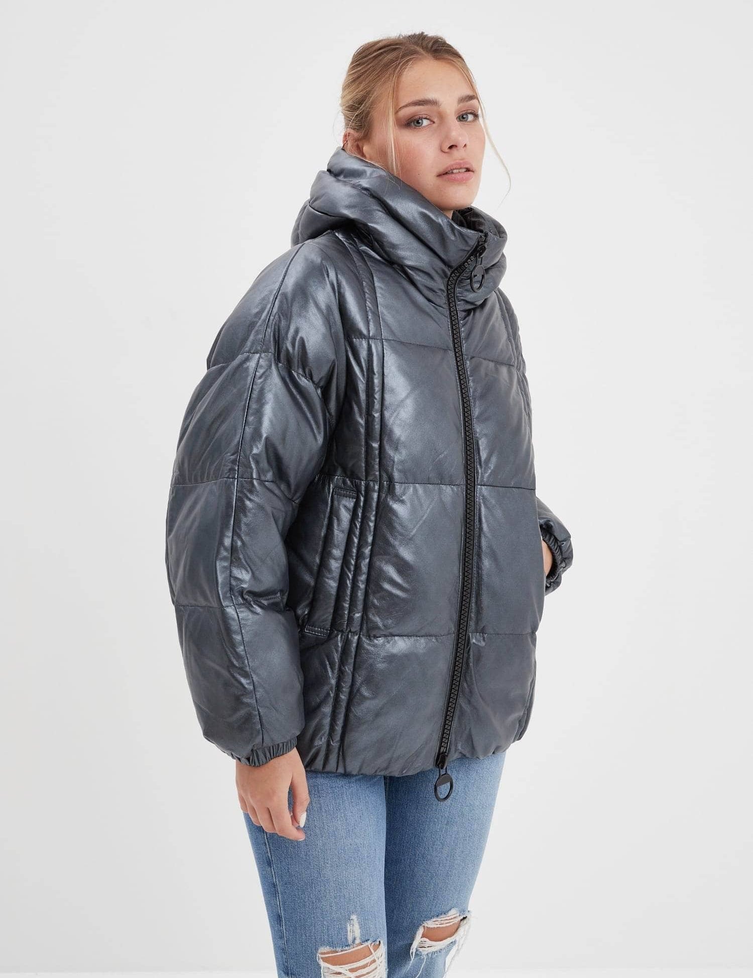 Femme portant une doudoune grise à capuche et un jean déchiré.
