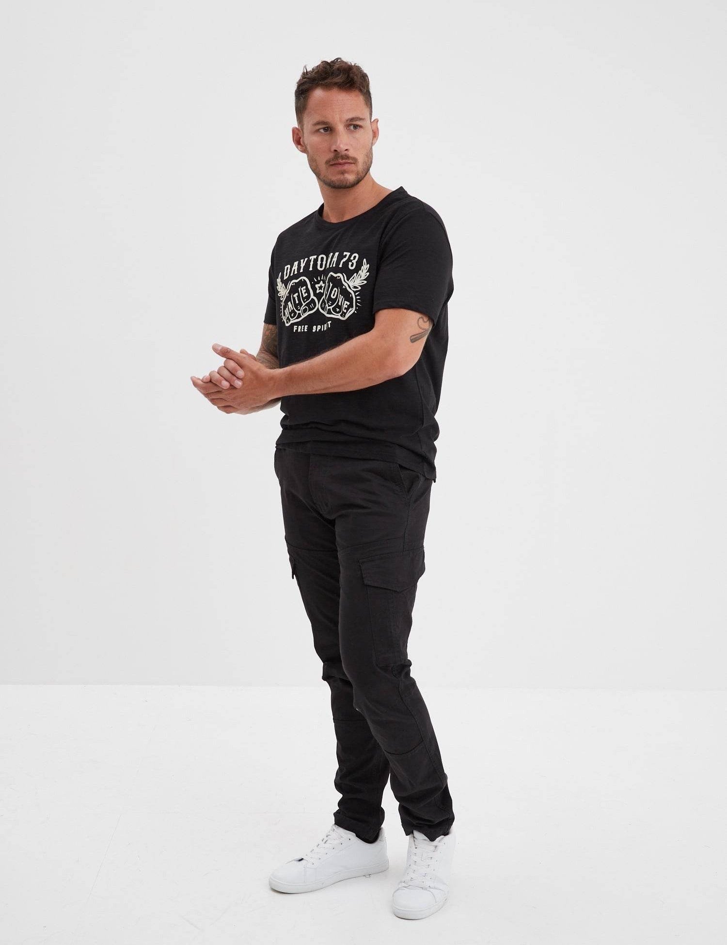 Homme portant un t-shirt noir et un pantalon cargo.