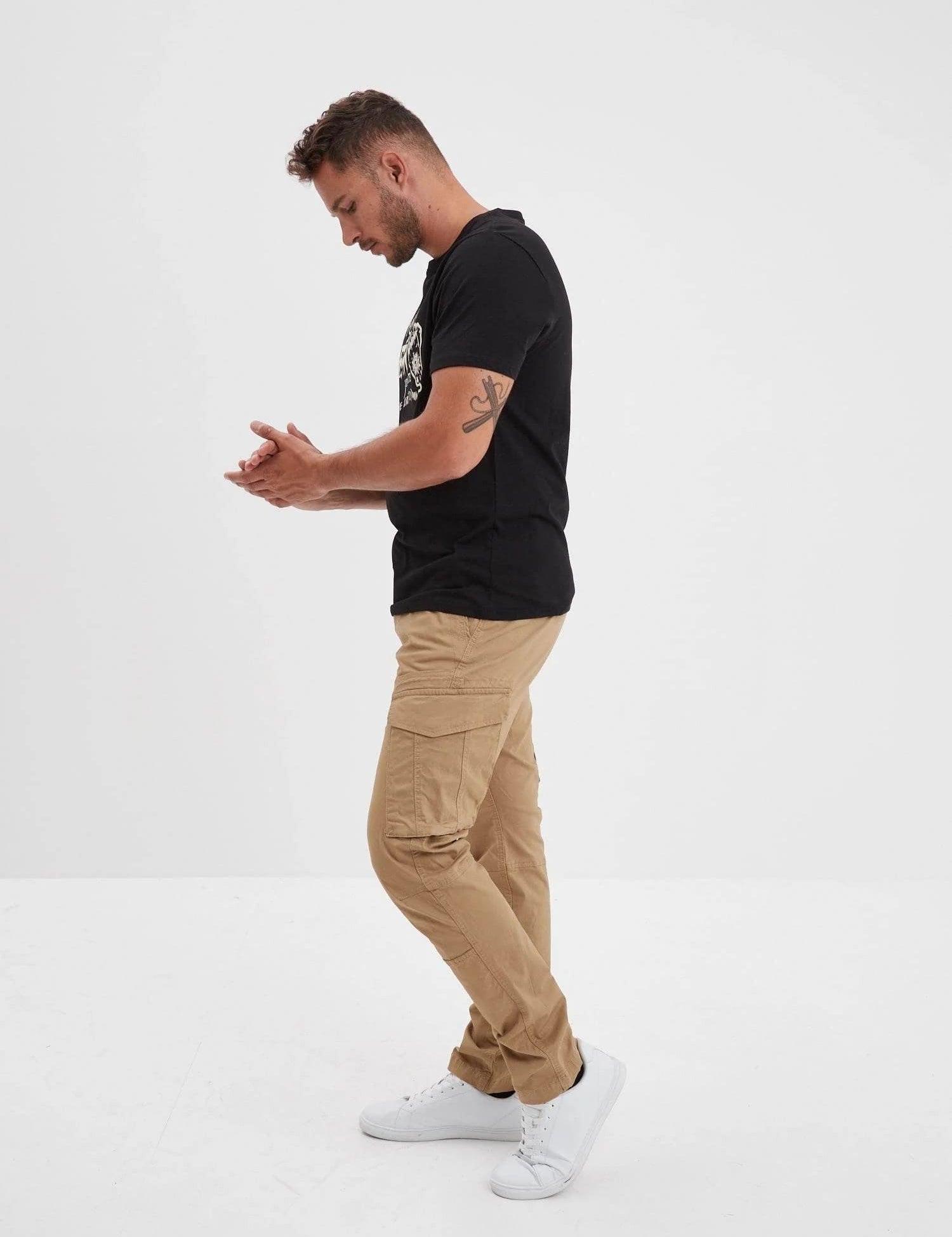 Homme en t-shirt noir et pantalon cargo beige.