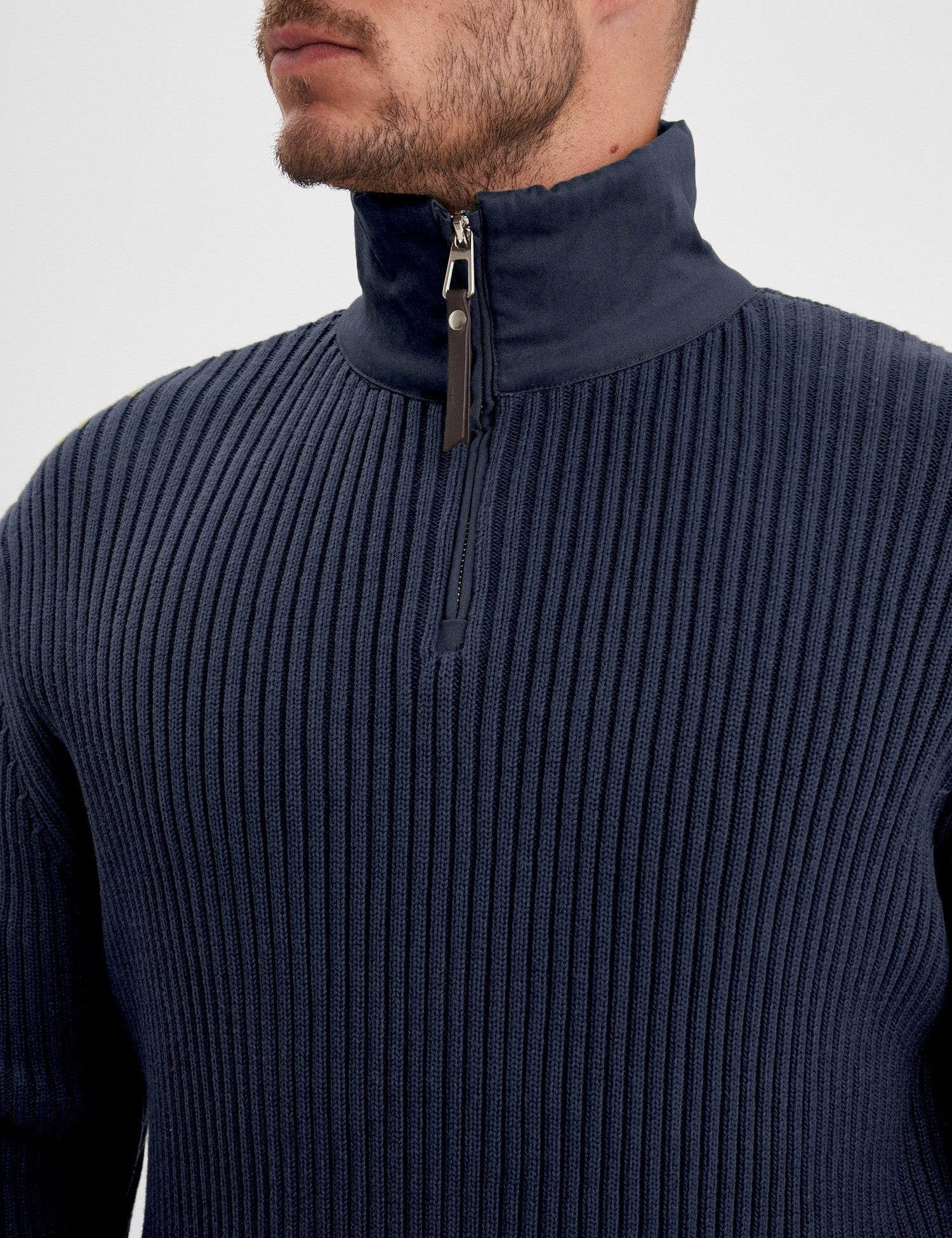 Gros plan sur le col zippé d'un pull bleu marine.