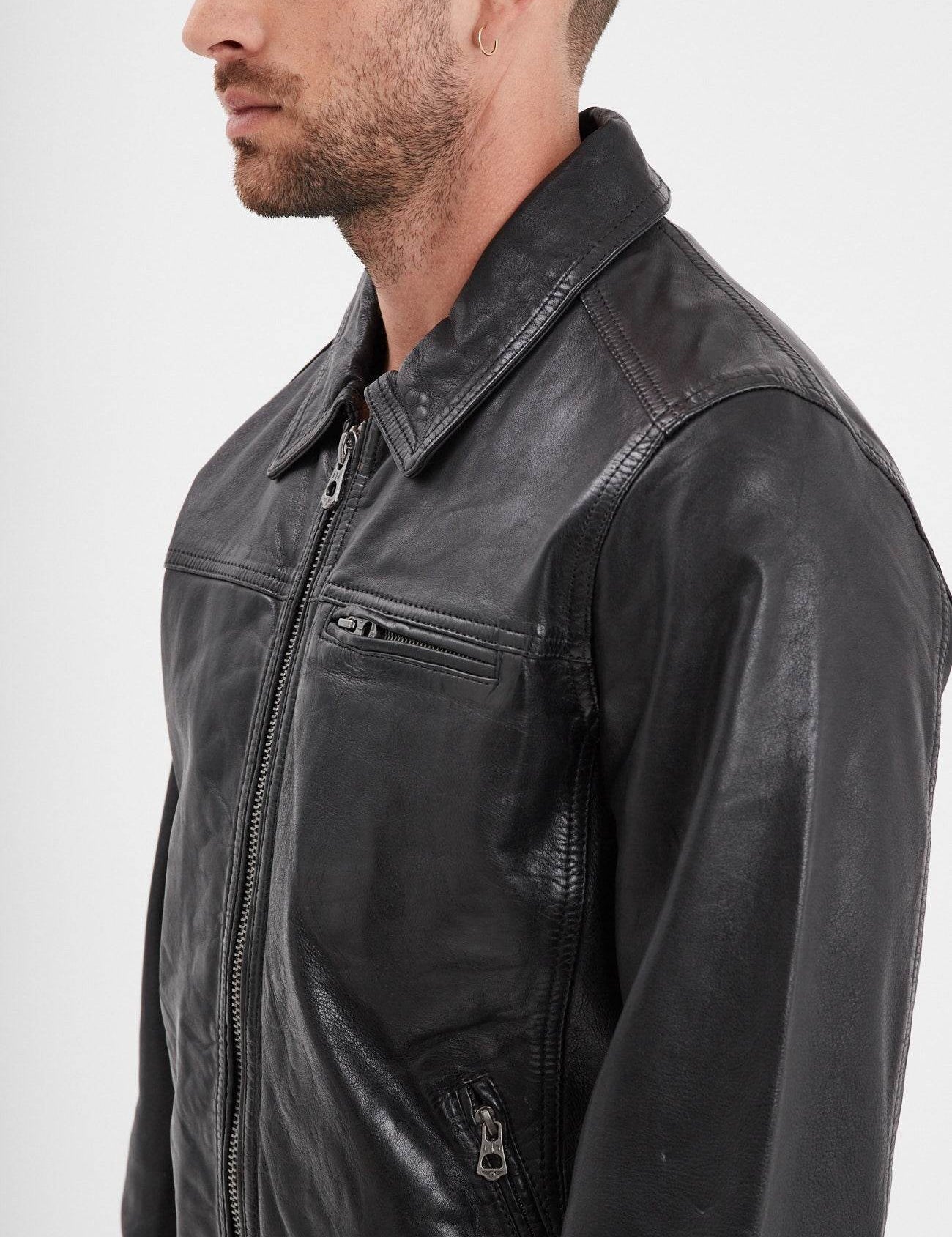Veste en cuir noir avec col chemise et fermetures éclair.