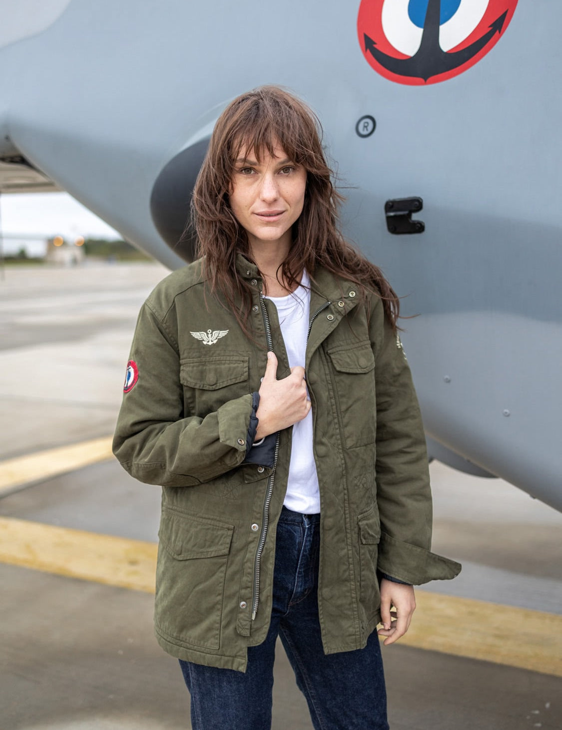 Veste militaire vert kaki avec écussons et broderies blanches.